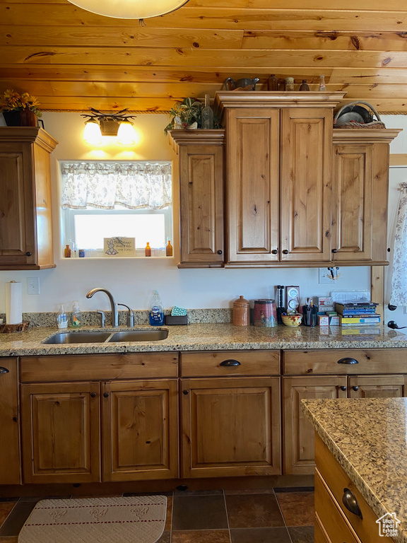Kitchen featuring a sink, light stone countertops, and wood ceiling