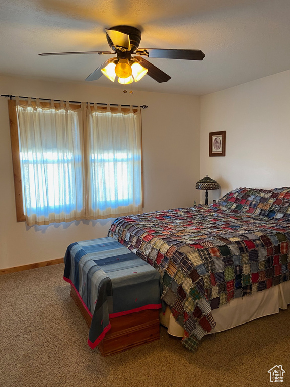 Carpeted bedroom featuring ceiling fan and baseboards