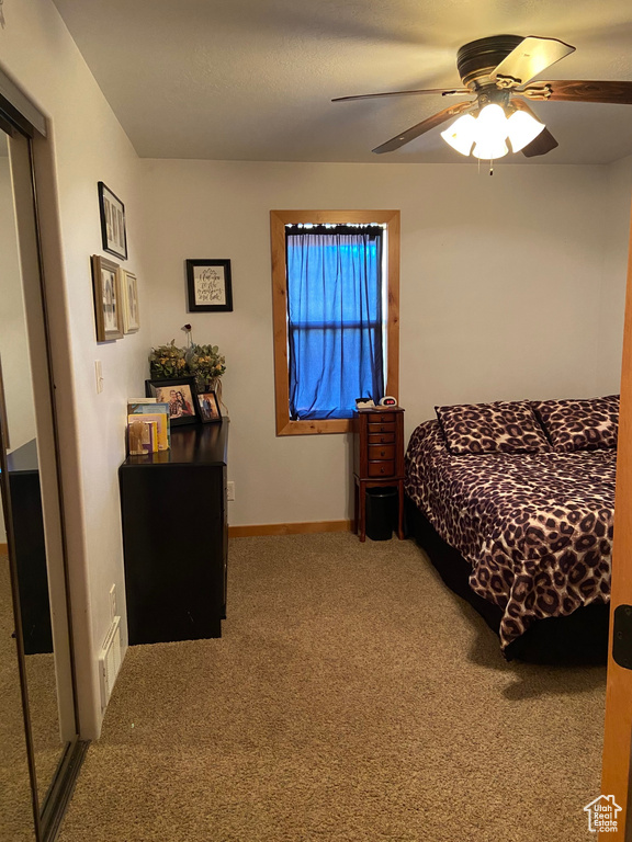 Carpeted bedroom with ceiling fan and baseboards