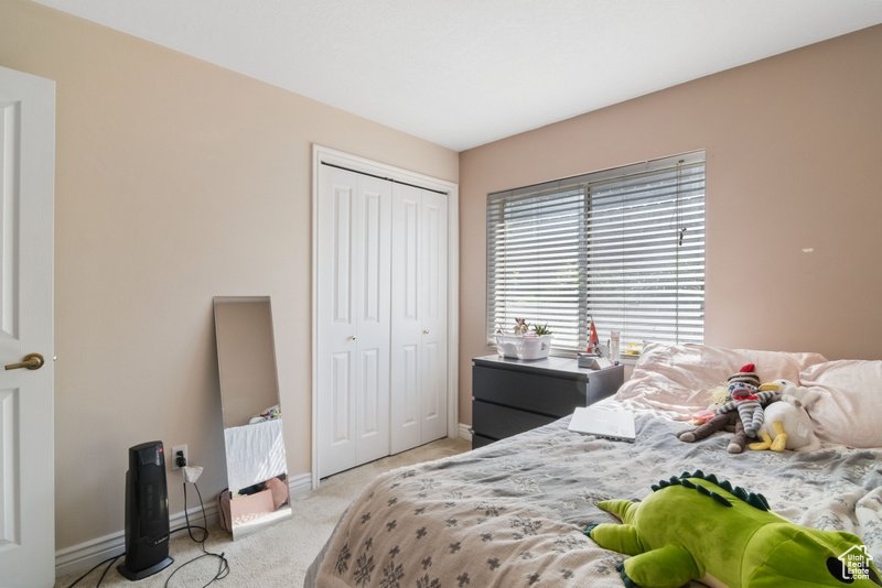 Bedroom with light colored carpet, baseboards, and a closet