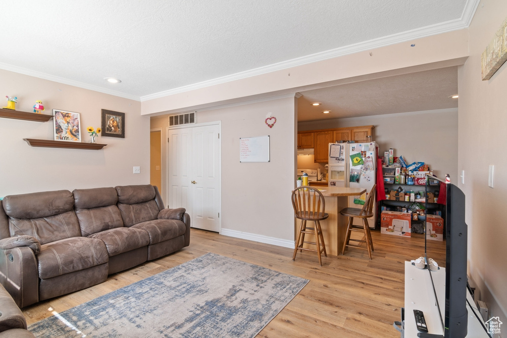 Living room with ornamental molding, light wood-type flooring, recessed lighting, and baseboards