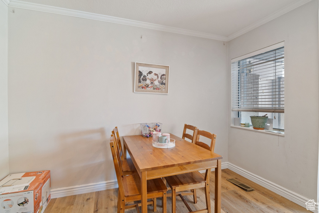Dining space with wood finished floors, ornamental molding, and baseboards