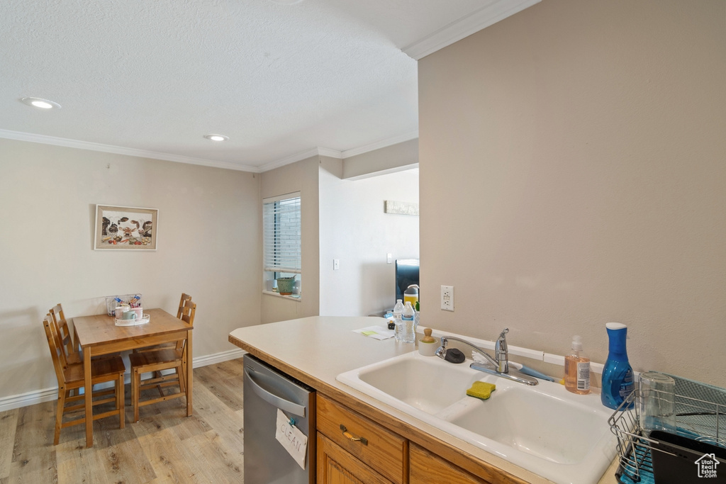 Kitchen featuring stainless steel dishwasher, a sink, ornamental molding, light wood-type flooring, and brown cabinetry