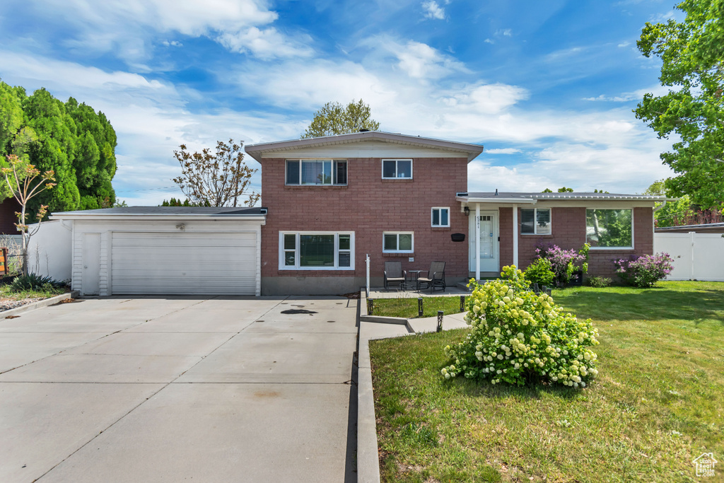 Tri-level home with an attached garage, concrete driveway, and brick siding