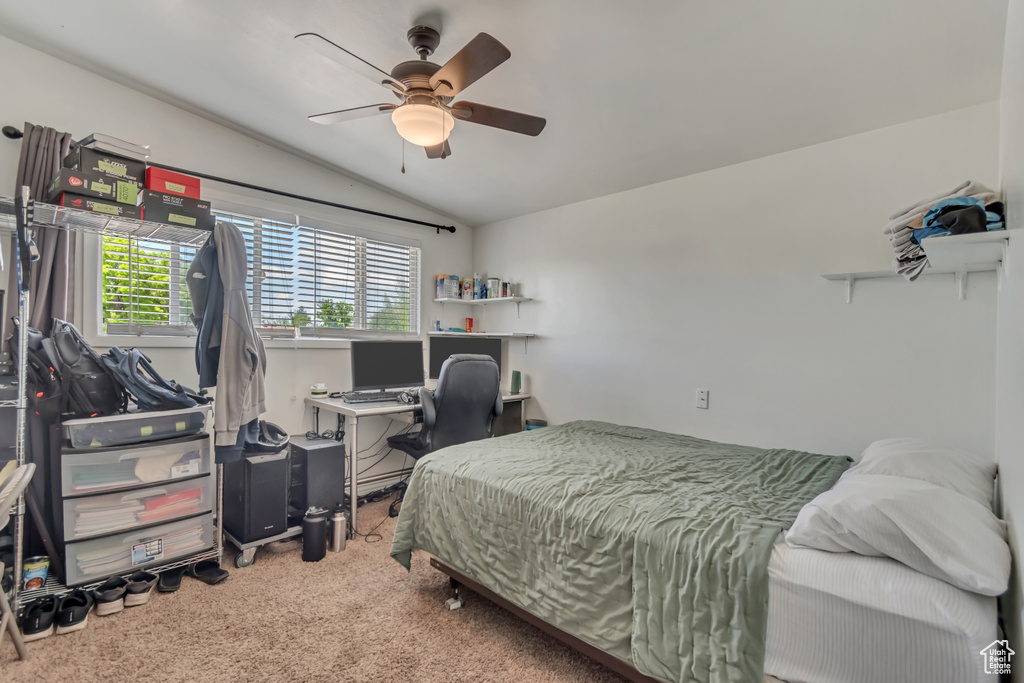 Carpeted bedroom featuring vaulted ceiling, ceiling fan, and a desk