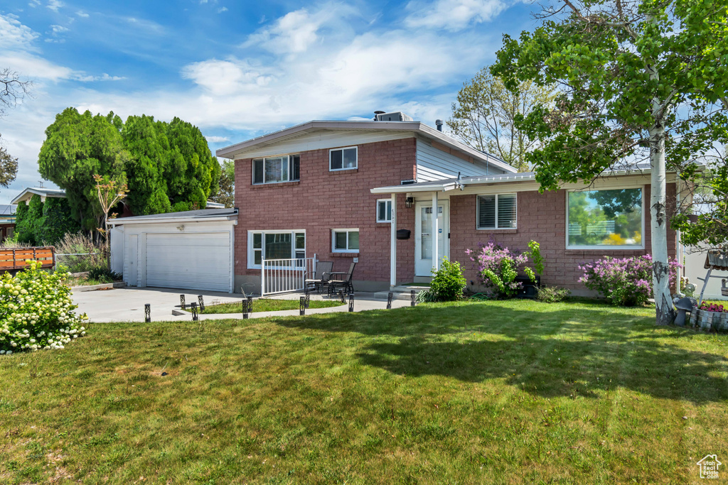 Split level home with an attached garage, concrete driveway, and a front lawn