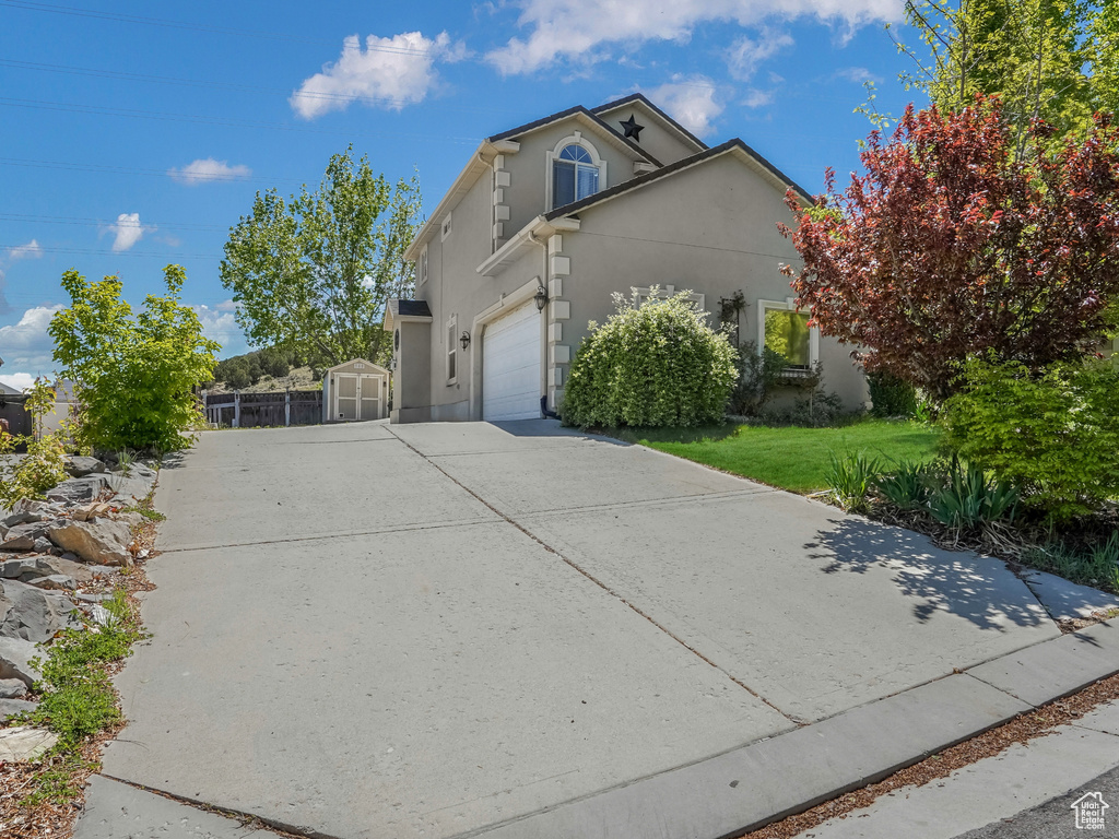 View of front facade featuring driveway, stucco siding, a front lawn, and a garage