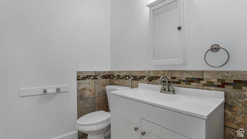 Bathroom with tile walls, toilet, vanity, and wainscoting