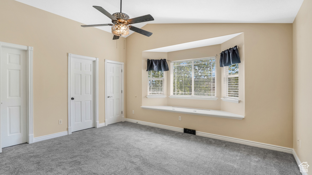 Unfurnished bedroom featuring carpet flooring, vaulted ceiling, two closets, baseboards, and ceiling fan