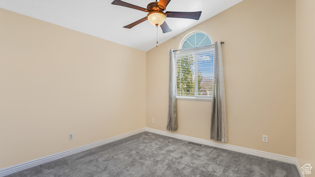 Empty room with ceiling fan, carpet floors, lofted ceiling, and baseboards