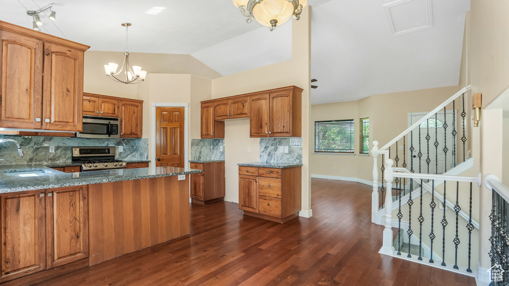 Kitchen featuring appliances with stainless steel finishes, brown cabinets, a sink, tasteful backsplash, and dark stone countertops