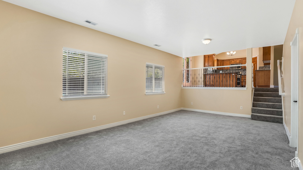 Unfurnished living room with carpet floors, stairs, and baseboards