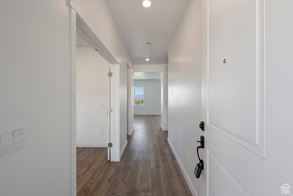 Hallway featuring baseboards, dark wood-style floors, and recessed lighting