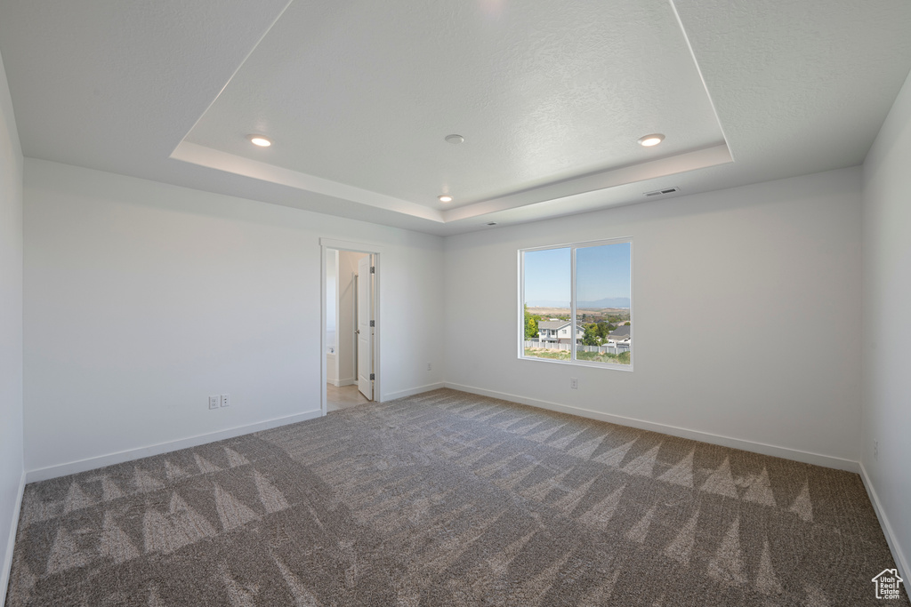 Carpeted empty room with a raised ceiling, baseboards, and recessed lighting