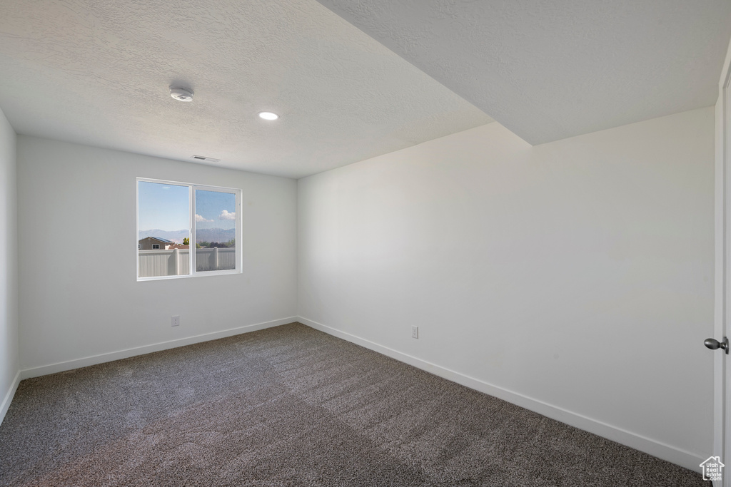 Empty room with baseboards, dark carpet, a textured ceiling, a smoke detector, and recessed lighting