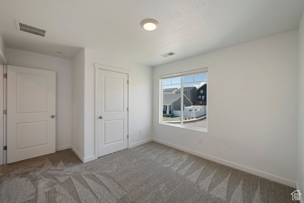 Unfurnished bedroom featuring carpet flooring, baseboards, and a textured ceiling