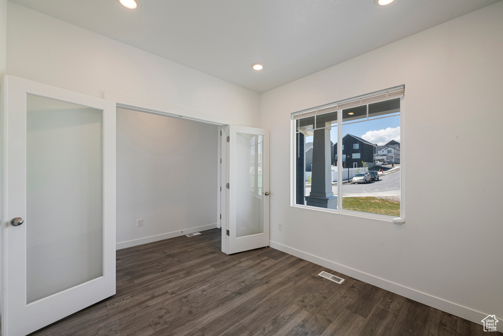 Empty room featuring dark wood-type flooring, baseboards, and recessed lighting