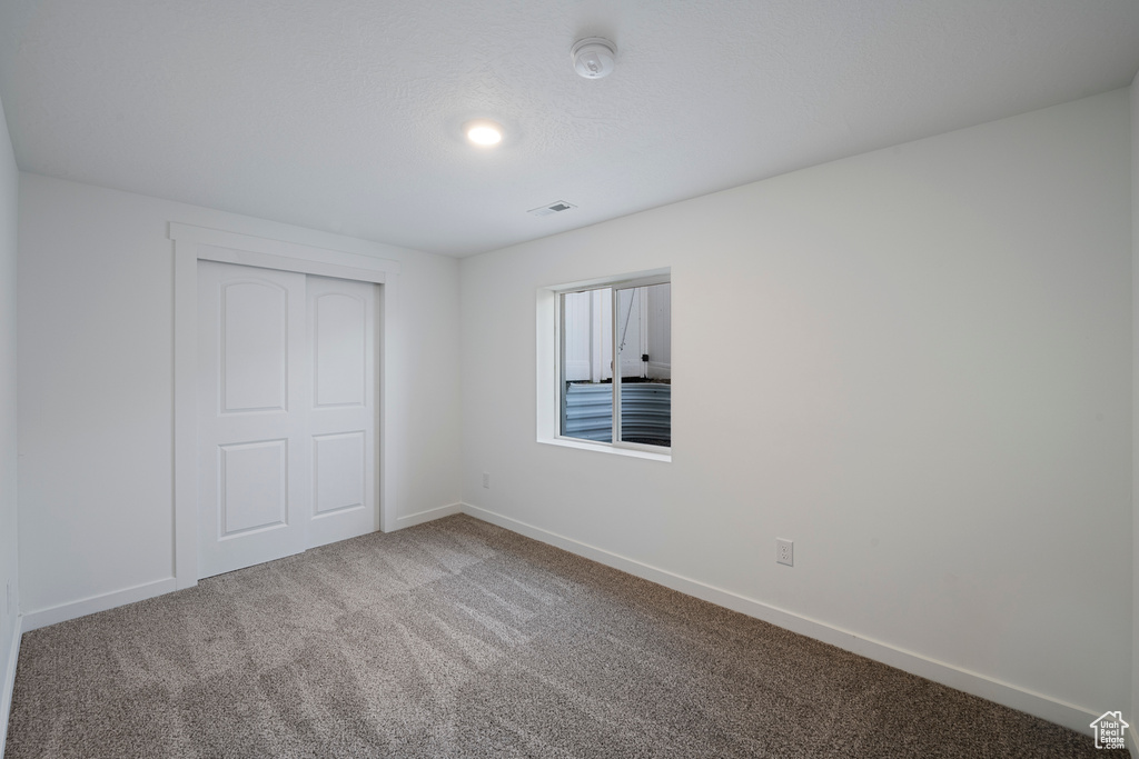 Unfurnished bedroom featuring carpet floors, baseboards, and a closet