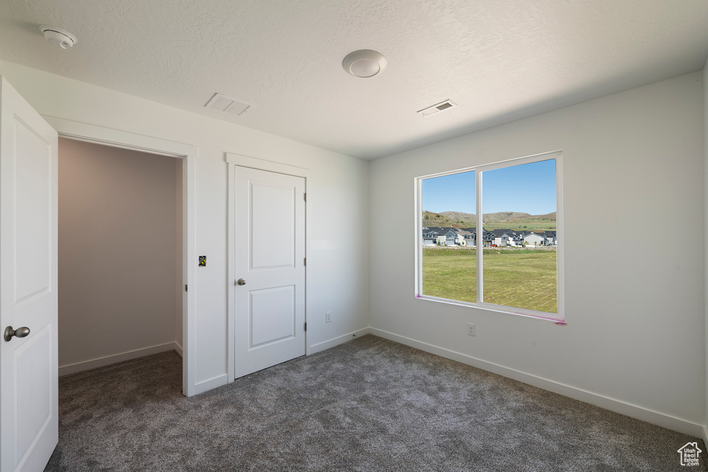 Unfurnished bedroom featuring dark colored carpet and baseboards