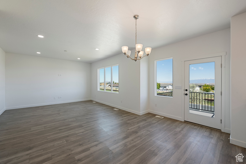 Unfurnished dining area with dark wood-style flooring, a chandelier, recessed lighting, and baseboards