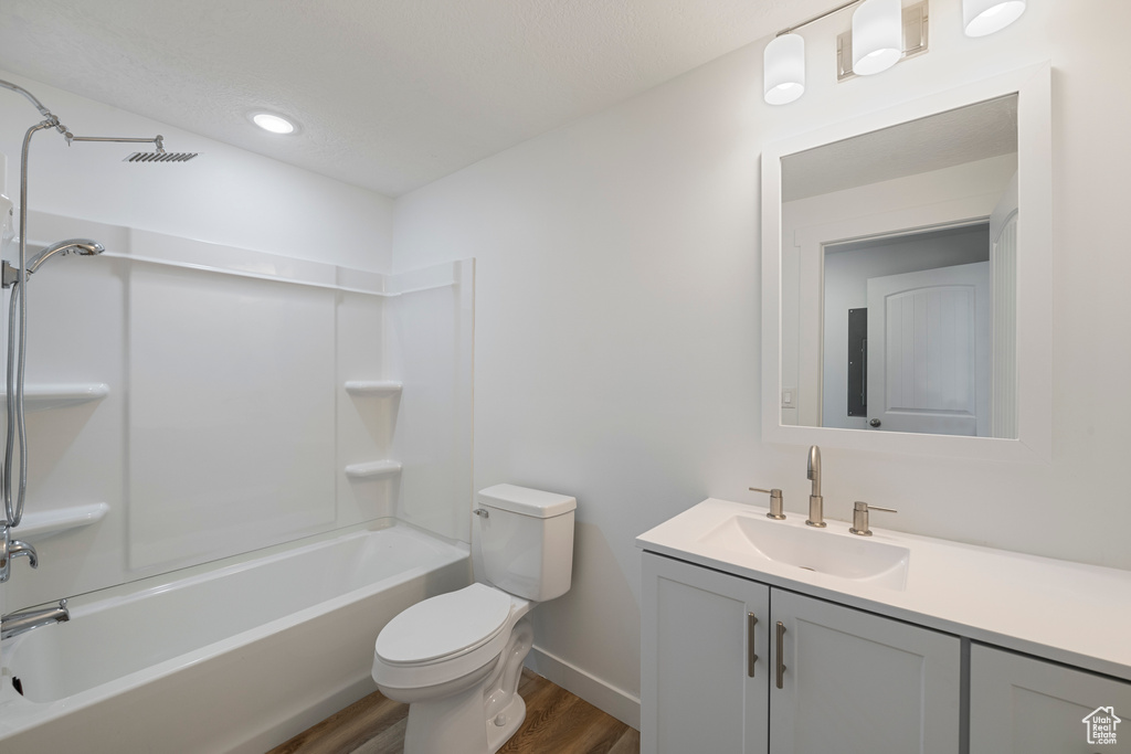 Bathroom featuring wood finished floors, toilet, vanity, baseboards, and shower / bath combination