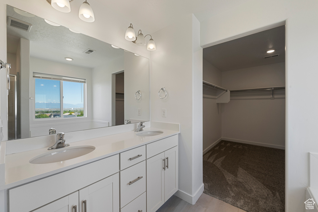 Bathroom with double vanity, baseboards, and a walk in closet