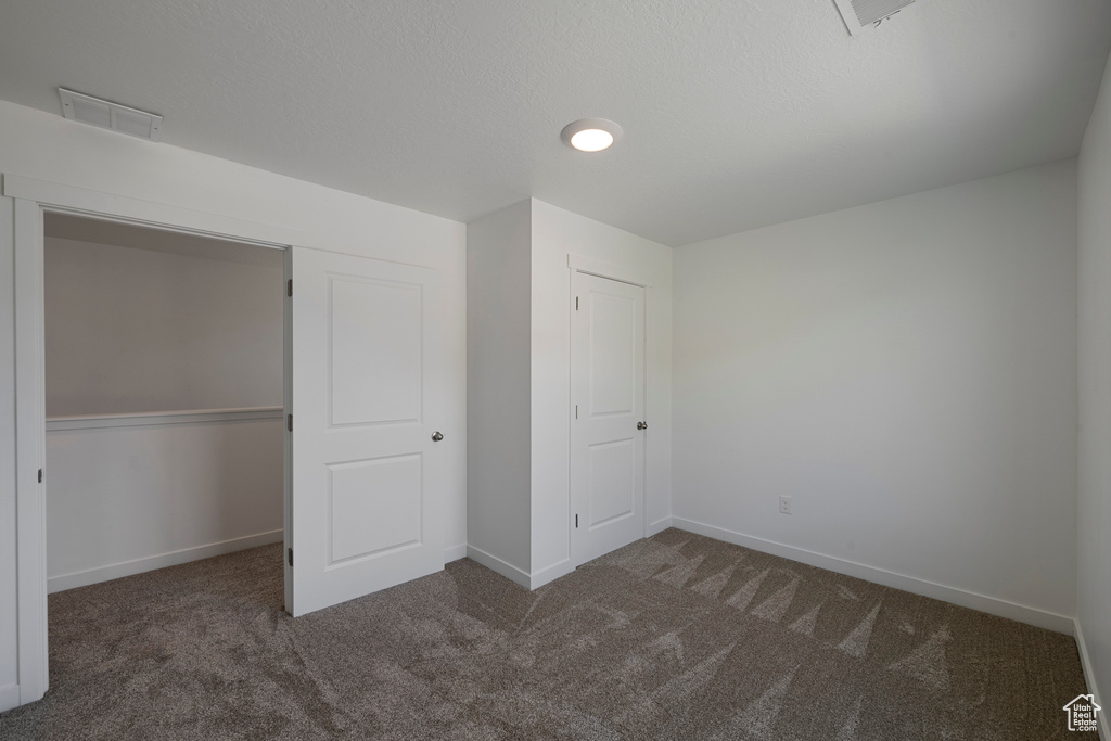 Unfurnished bedroom featuring carpet, baseboards, and a closet