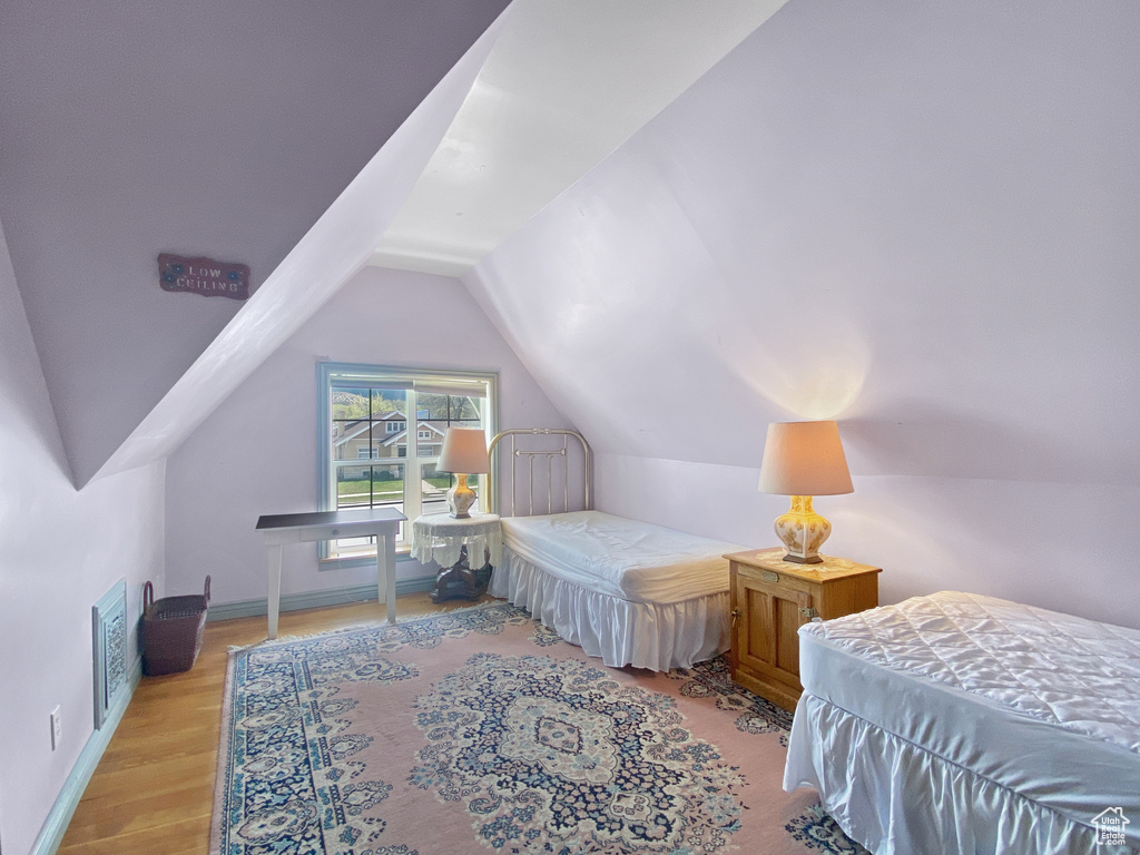 Bedroom with lofted ceiling, wood finished floors, and baseboards