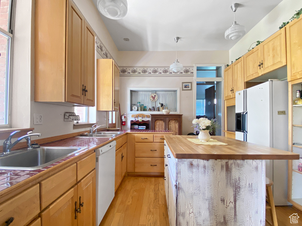 Kitchen featuring white appliances, a sink, wood counters, and a breakfast bar
