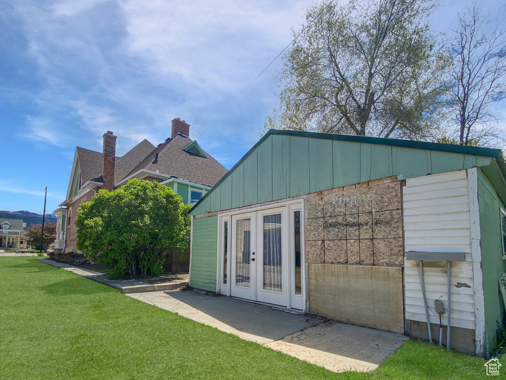 Back of house with french doors, a lawn, board and batten siding, and a patio