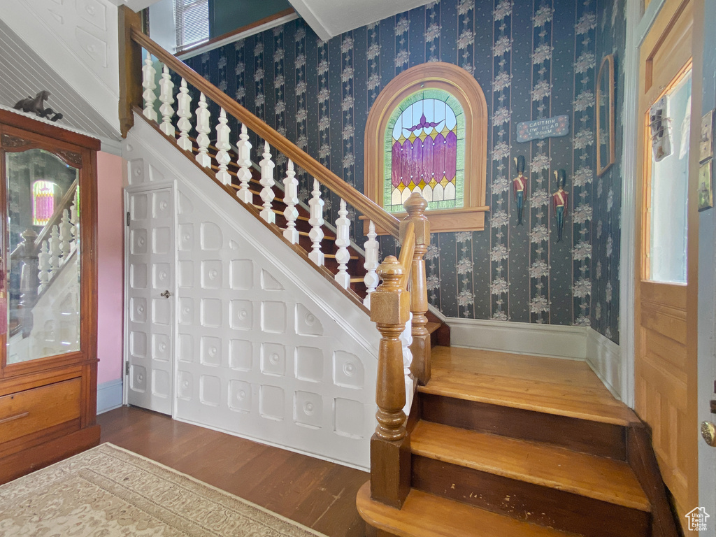 Stairs featuring wallpapered walls and wood finished floors