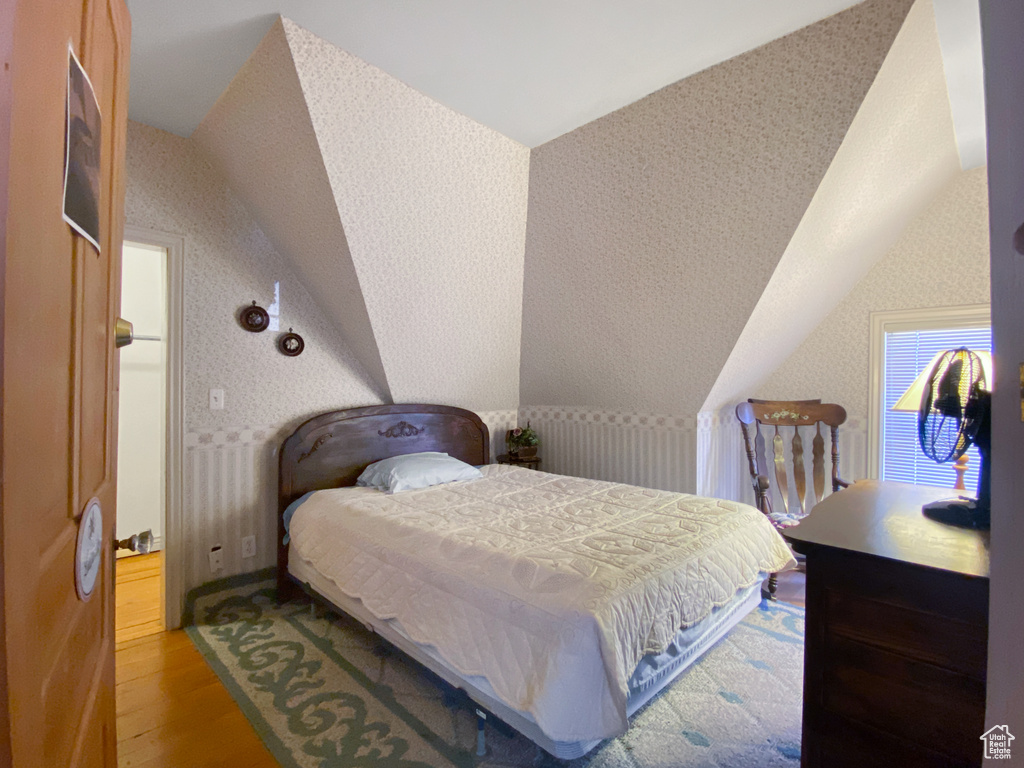 Bedroom featuring lofted ceiling, light wood finished floors, and radiator