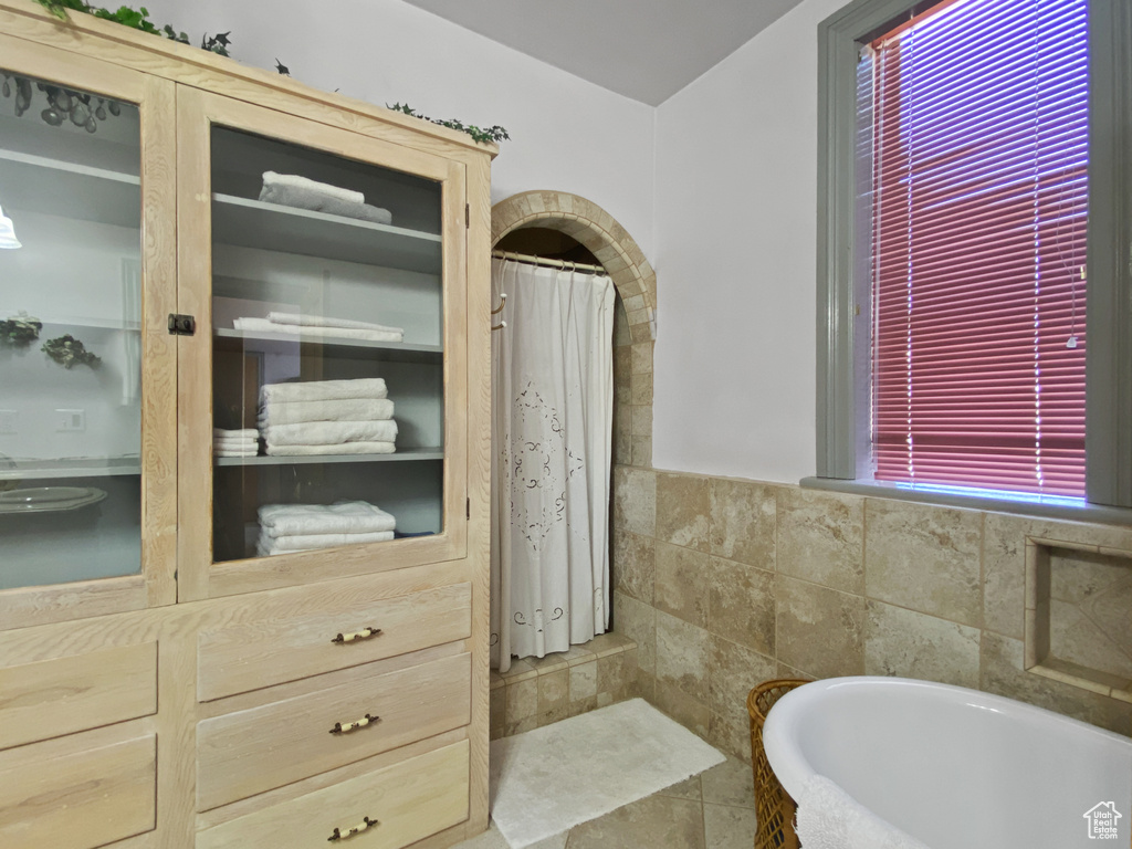 Full bath with a bath, a shower with curtain, and tile walls