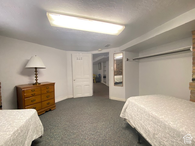 Bedroom featuring dark colored carpet, baseboards, and a textured ceiling