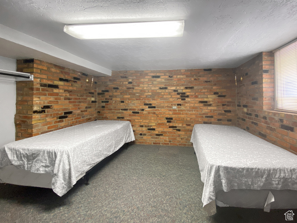 Bedroom featuring brick wall, carpet, and a textured ceiling