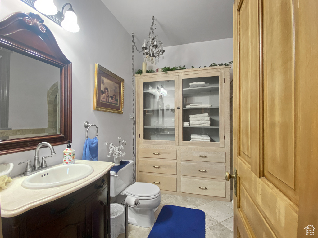 Bathroom featuring toilet, vanity, tile patterned floors, and a chandelier