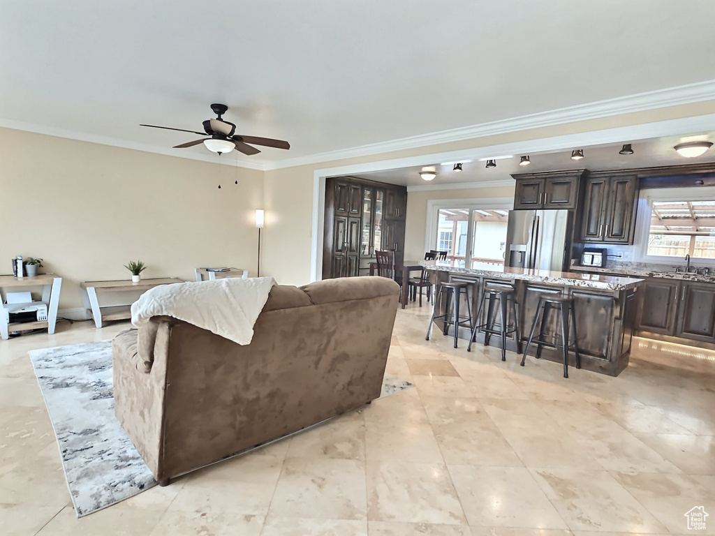 Living room featuring ceiling fan, ornamental molding, and light tile patterned floors