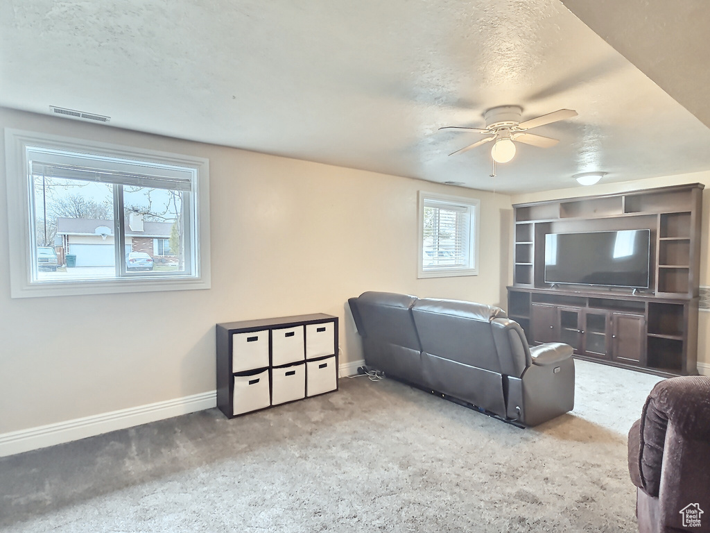 Living room with ceiling fan, carpet floors, and baseboards