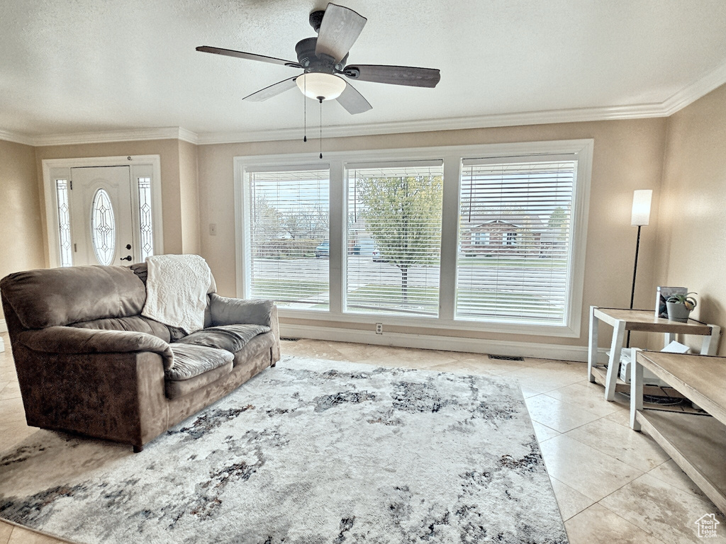 Living area with plenty of natural light, ornamental molding, a ceiling fan, and light tile patterned flooring