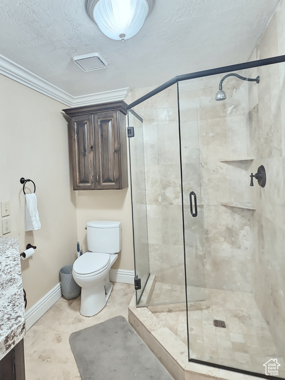 Bathroom with toilet, a textured ceiling, baseboards, a stall shower, and ornamental molding