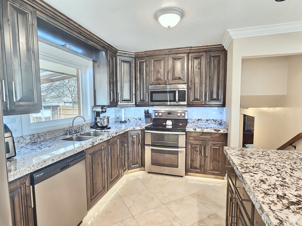 Kitchen featuring stainless steel appliances, a sink, dark brown cabinetry, and crown molding