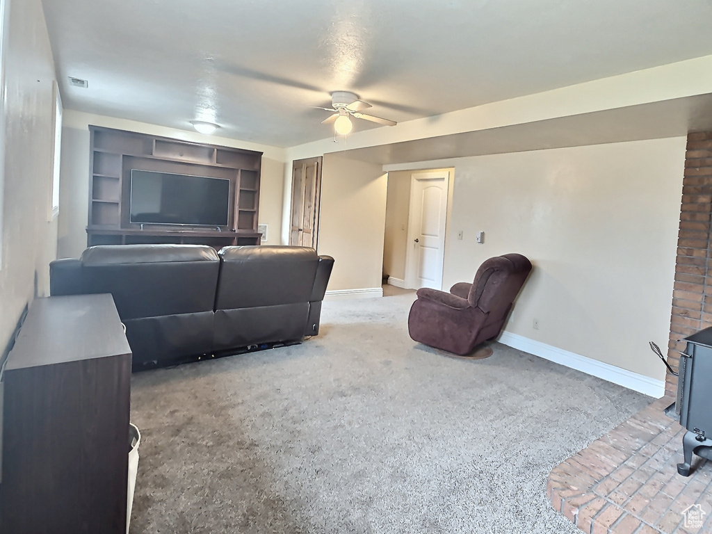 Carpeted living area with a ceiling fan, baseboards, a wood stove, and built in shelves