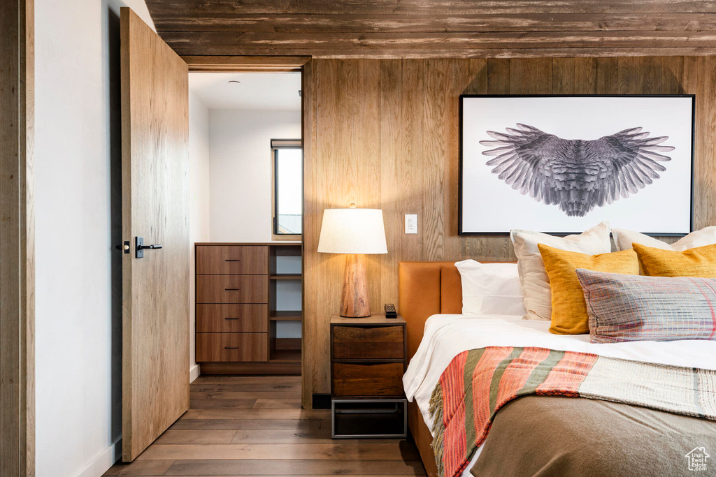 Bedroom featuring wood-type flooring, wooden walls, and baseboards