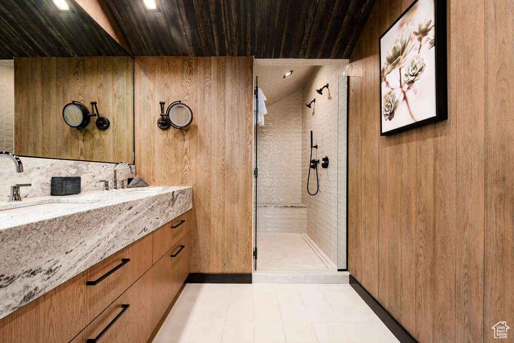 Bathroom with a tile shower, vanity, wood ceiling, and tile patterned flooring