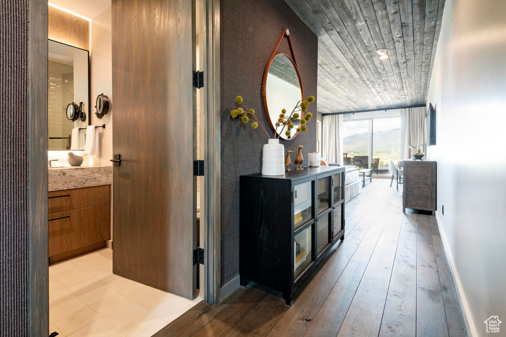 Corridor with expansive windows, wood ceiling, light wood finished floors, and baseboards