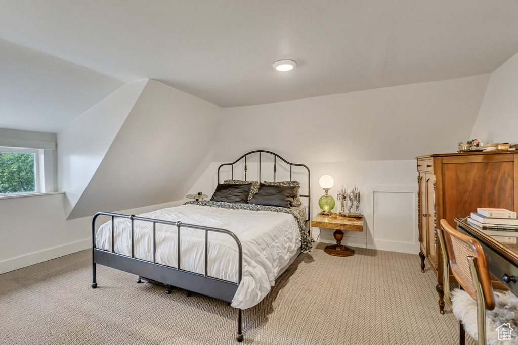 Carpeted bedroom with lofted ceiling and baseboards