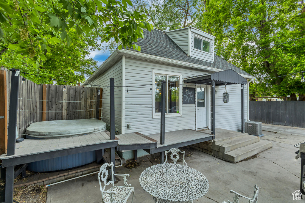 Rear view of house with a fenced backyard, a shingled roof, a patio area, central AC unit, and a wooden deck