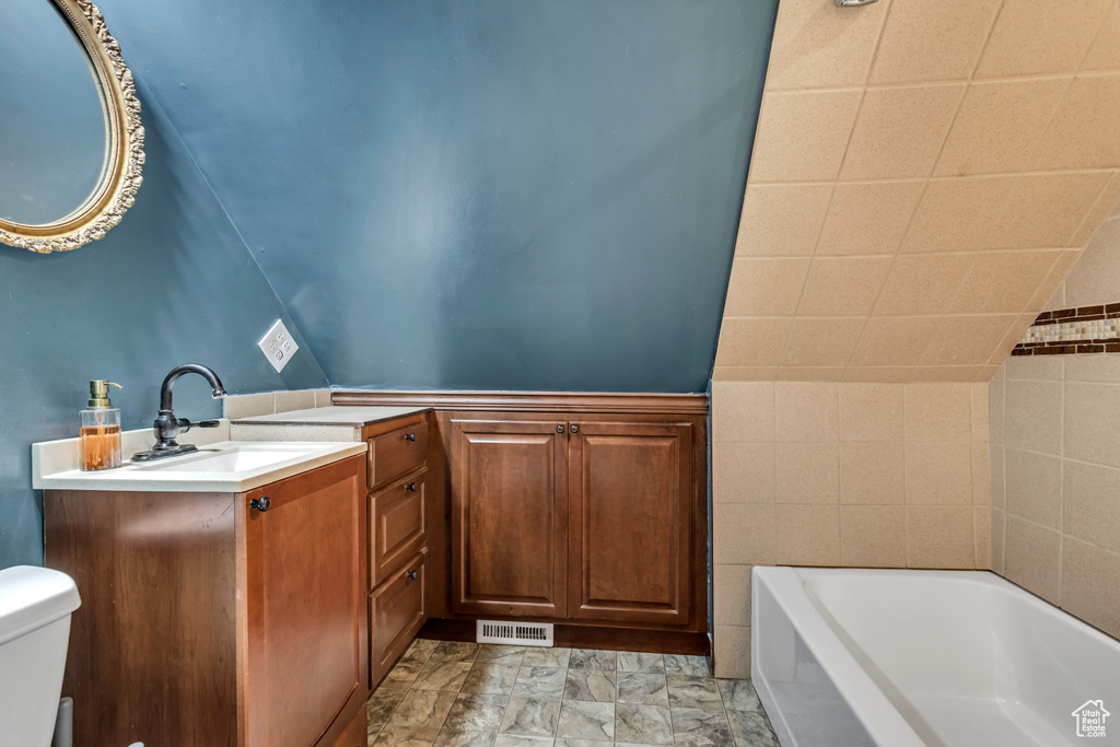Full bathroom featuring toilet, a tub, and vanity