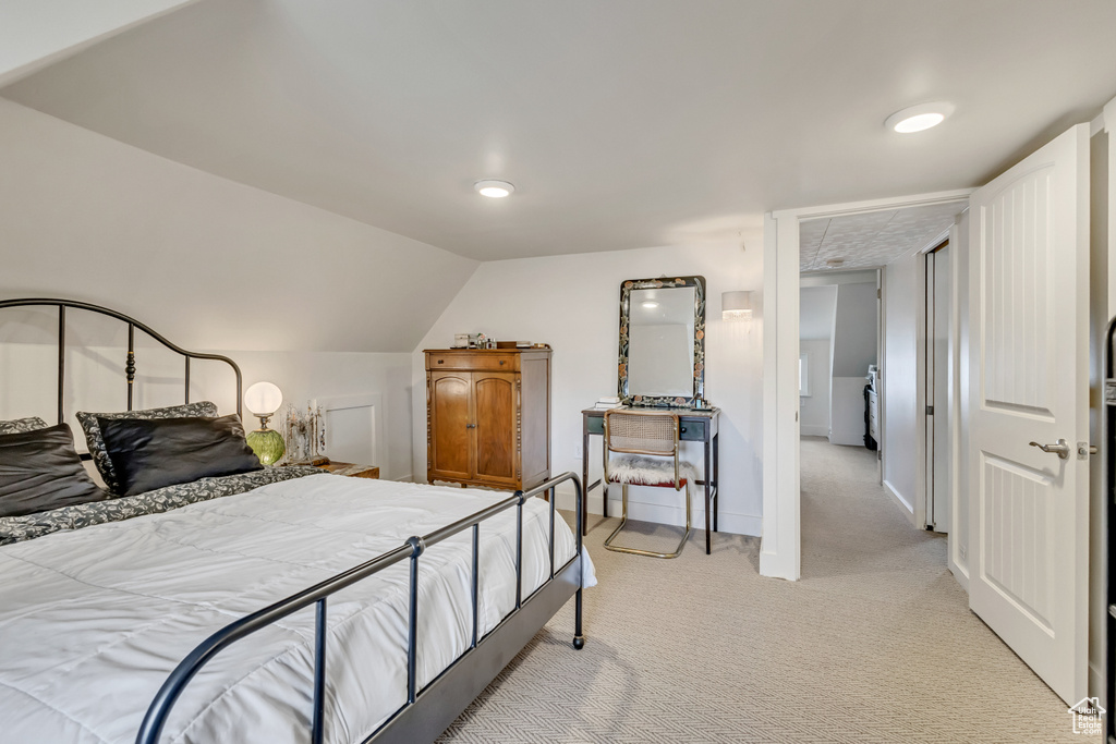 Bedroom featuring light colored carpet, vaulted ceiling, and baseboards