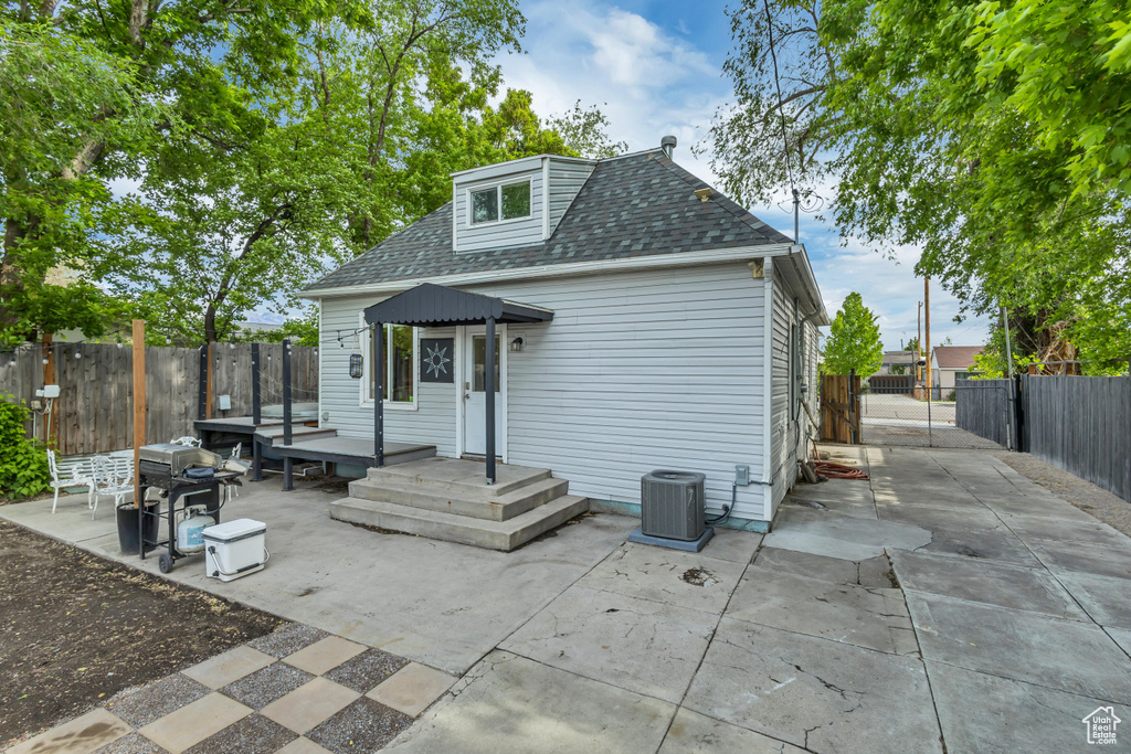 Rear view of property featuring a patio, a fenced backyard, central AC unit, and roof with shingles